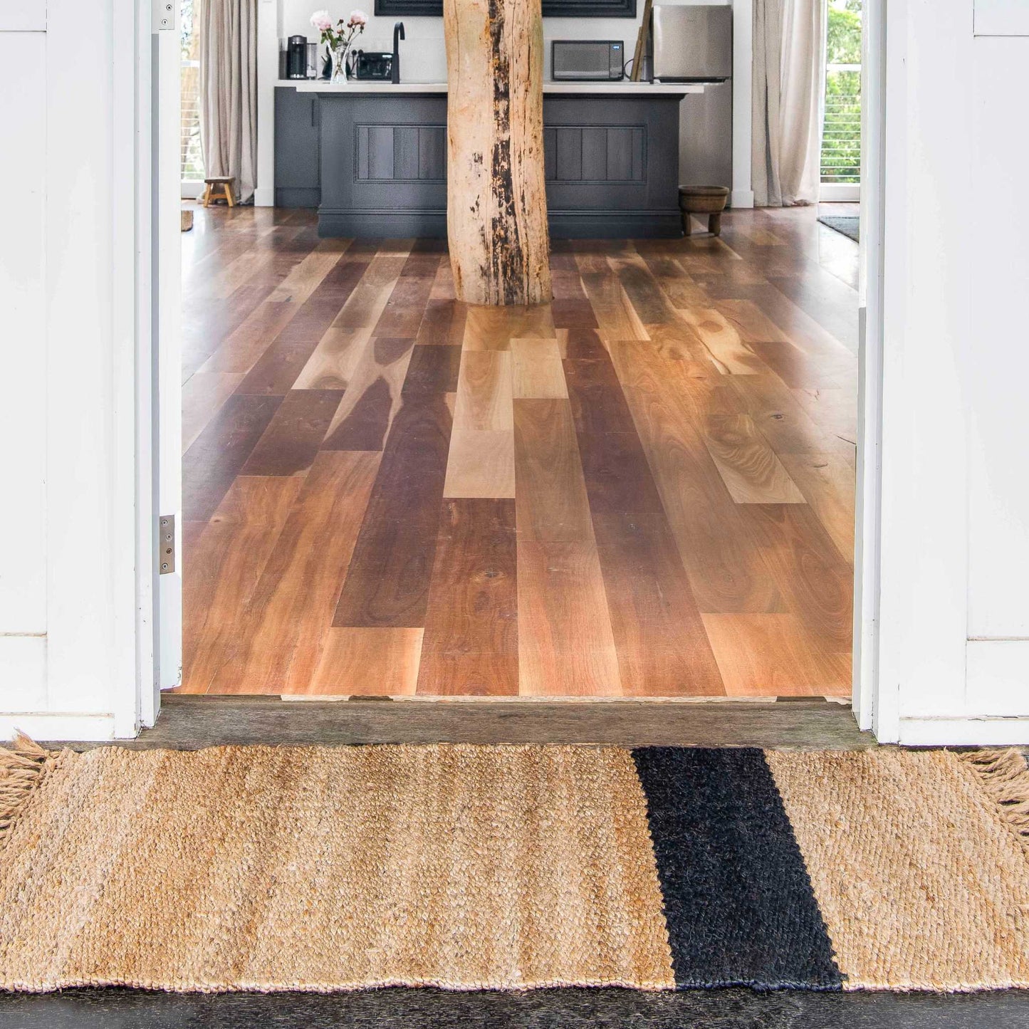 A natural jute Baxter rug with a graphite stripe, placed at the entrance to a home.