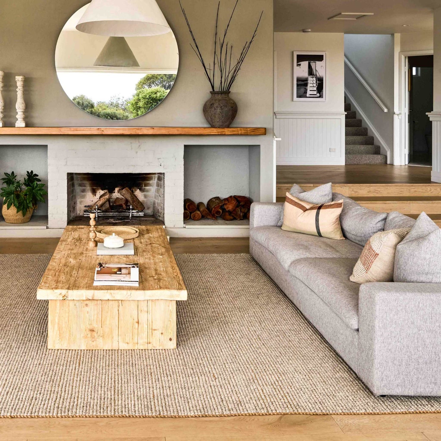 Carter handcrafted, grey and white wool and jute area rug on a wooden floor in a lounge room with a fire place.