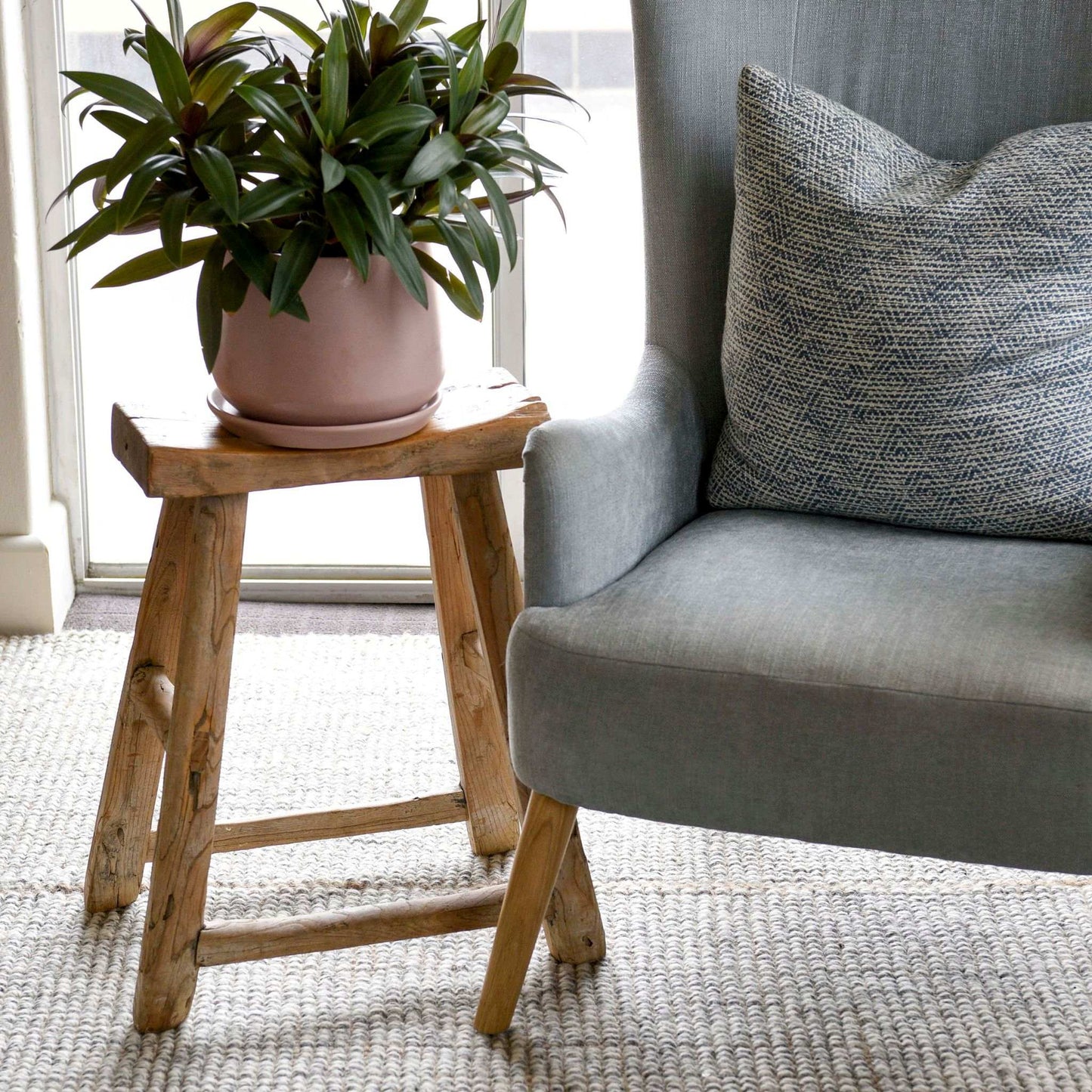 Gray armchair sitting on a Carter handcrafted, grey and white heathered wool and jute rug in a living room.