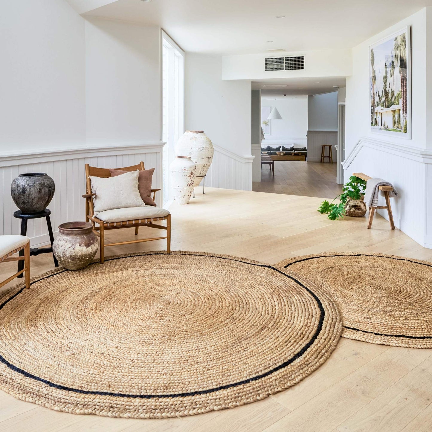 Elegant large living space with two Cooper hand braided jute round rugs sitting on a wooden floor.