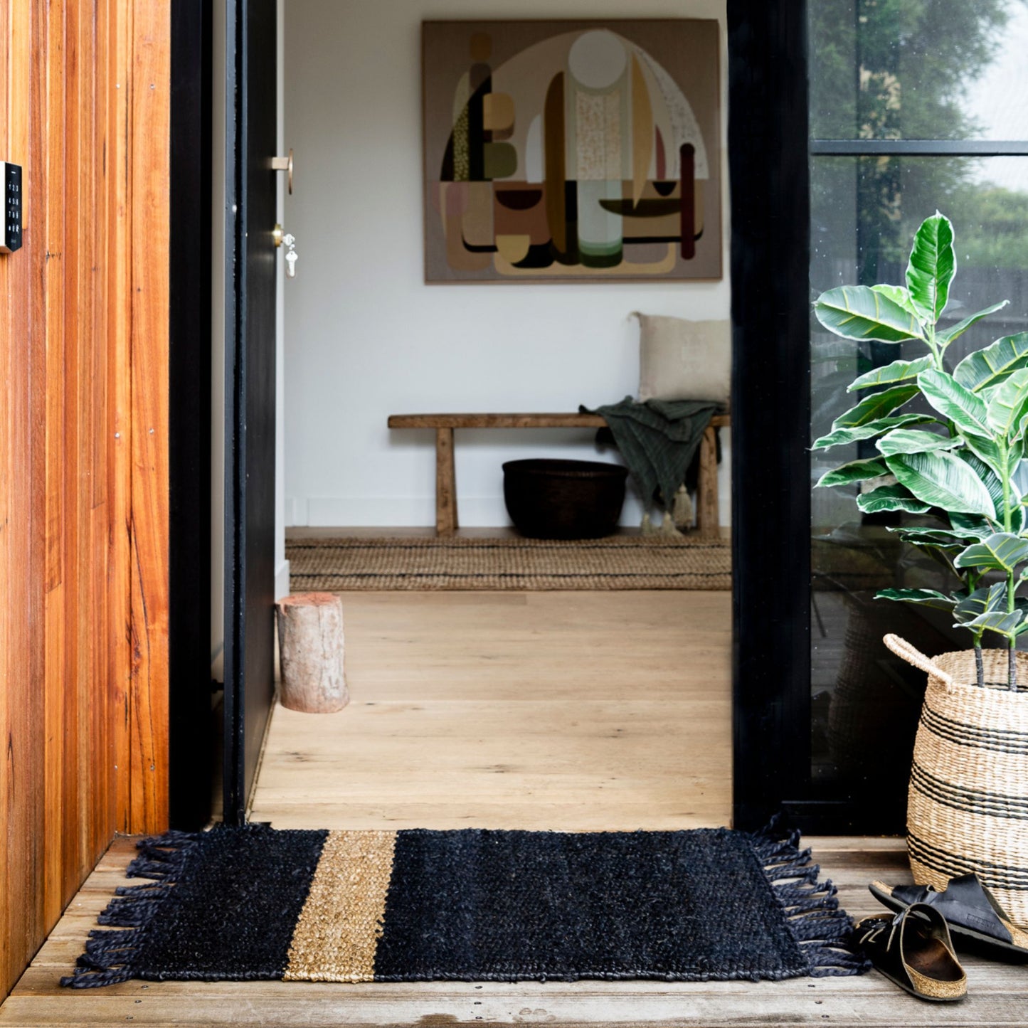 Handcrafted Irving stripe jute flatweave rug on a wooden decking at an entrance to a home.