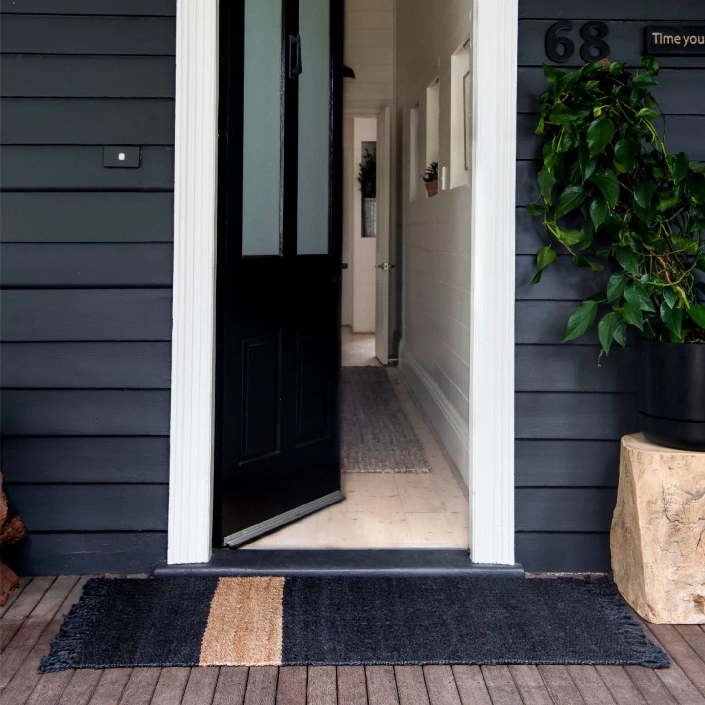 Handcrafted Irving stripe jute flatweave rug on a wooden decking at an entrance to a home.