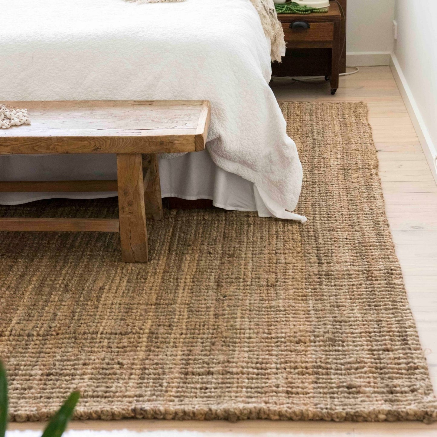 Handcrafted natural bouclé jute area rug in a coastal bedroom.