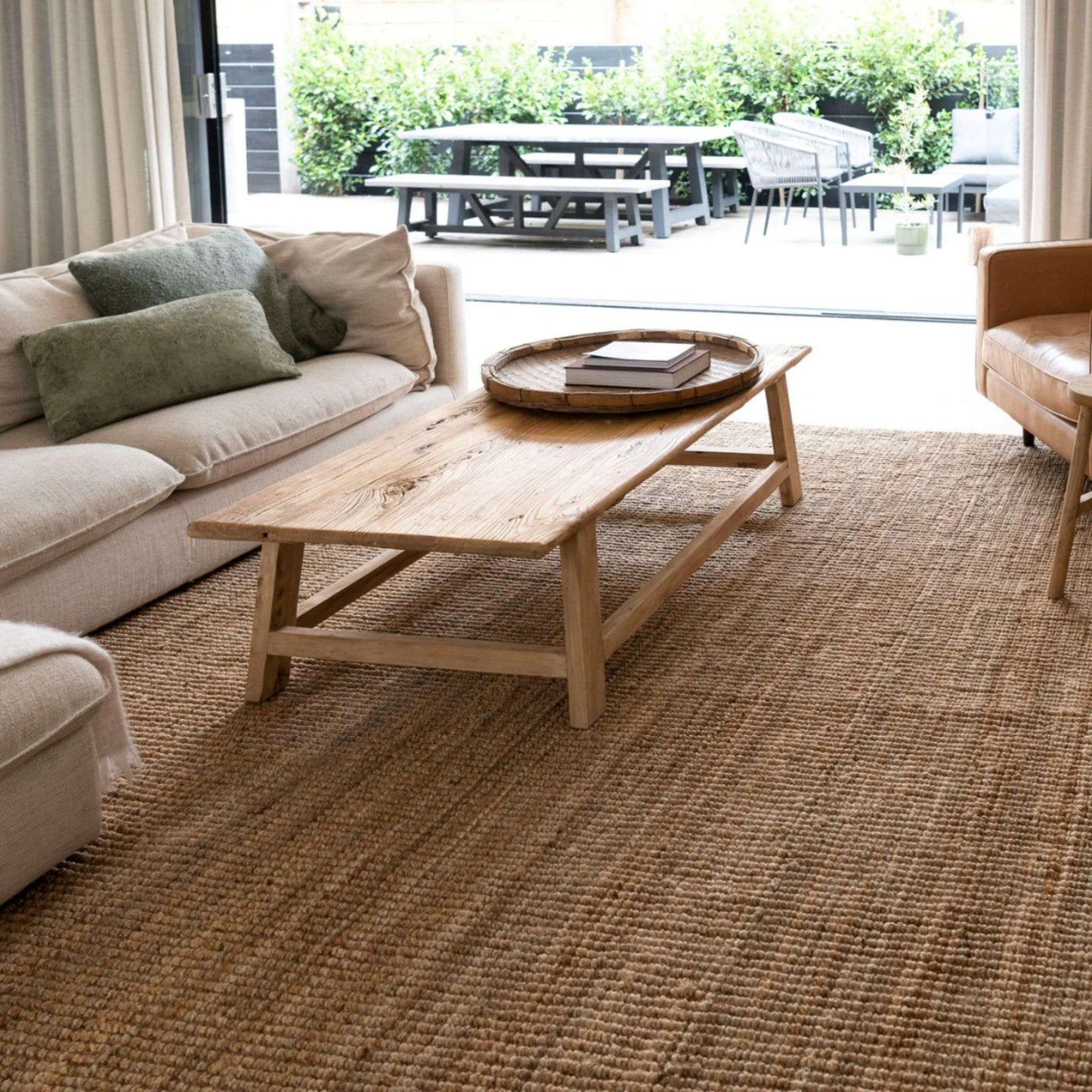Handcrafted natural bouclé jute area rug in a coastal living room with patio outlook.