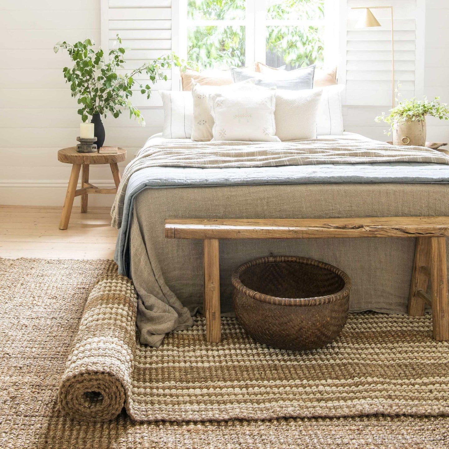 Handcrafted Osbourne natural chunky jute bouclé runner rug with white stripes layered over a natural jute rug in a cozy sunlit bedroom.