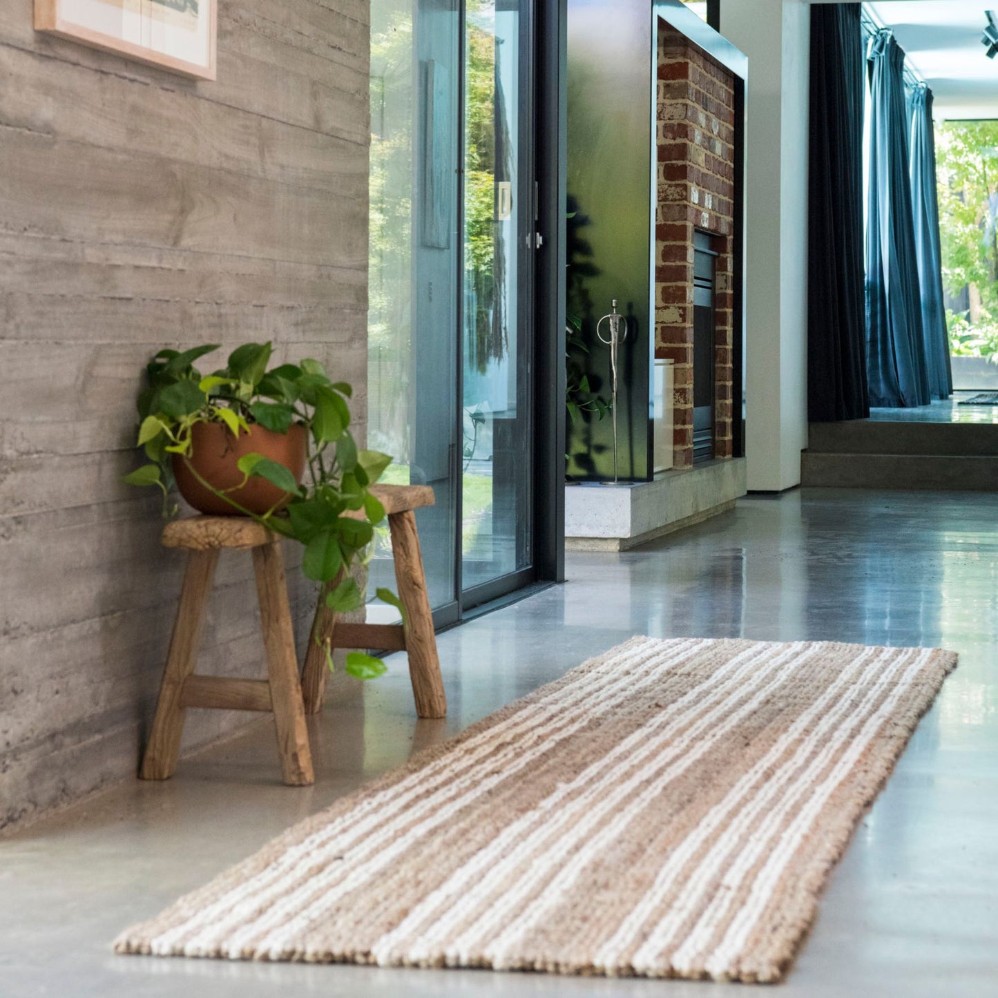 Handcrafted Osbourne natural chunky jute bouclé runner rug with white stripes on a polished concrete floor in a modern home.