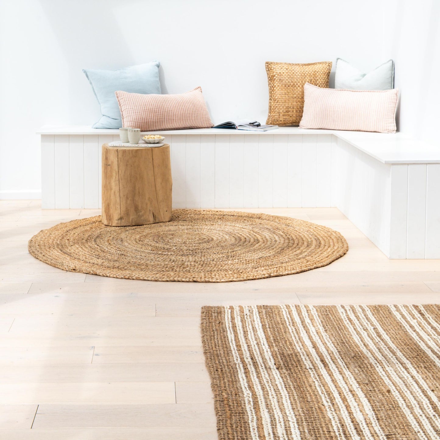 Handcrafted Osbourne natural chunky jute bouclé area rug with white stripes in nook space with white walls and a cozy reading area.