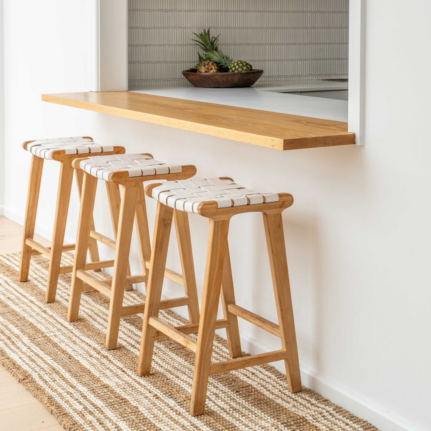Handcrafted Osbourne natural chunky jute bouclé runner rug with white stripes at a modern kitchen bench under modern white stools.
