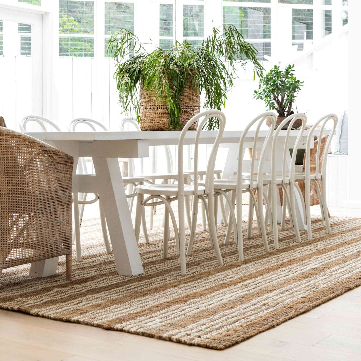 Osbourne natural chunky jute bouclé rug with white stripes sitting under a dining table in a coastal home.