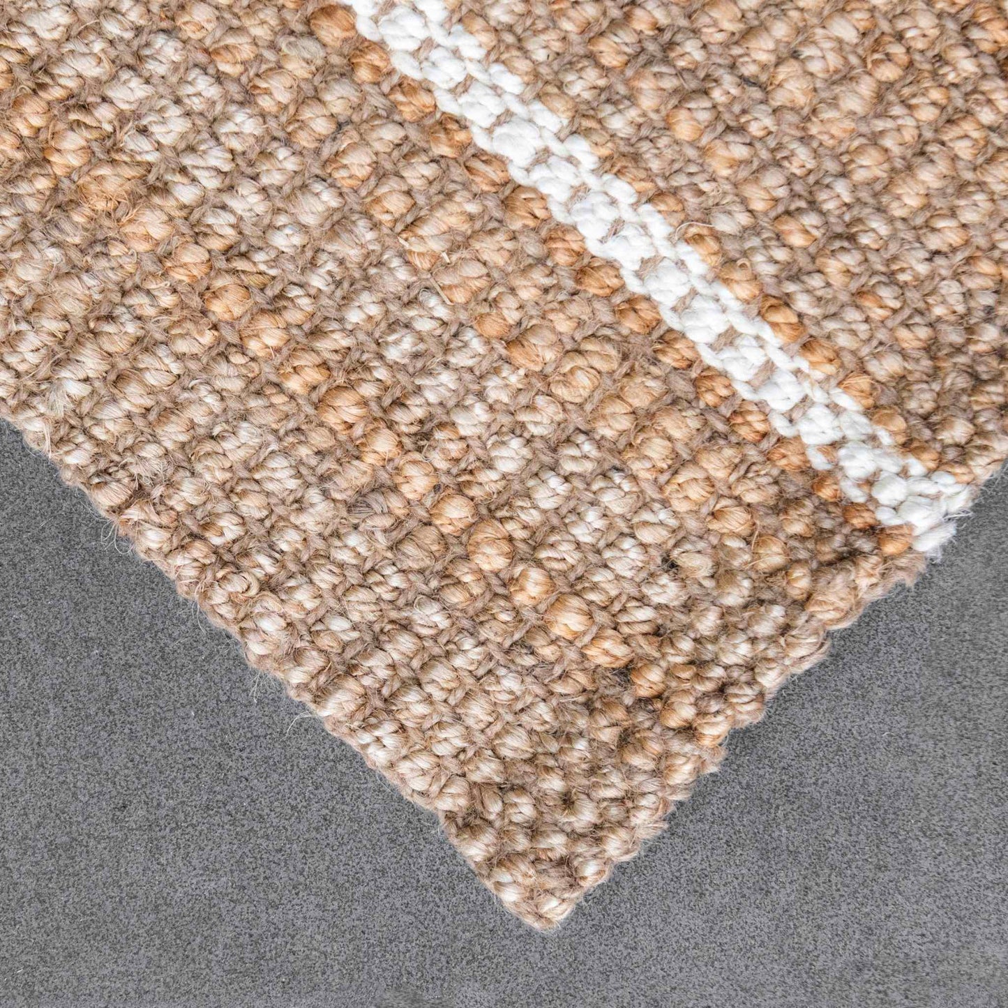 Close-up of the woven bouclé texture and white stripes on the Robinson jute runner rug on slate background.