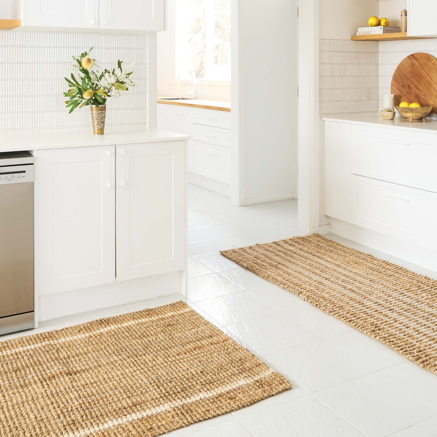 Robinson runner rug in natural bouclé jute with two white stripes on a tile floor in a white modern kitchen.