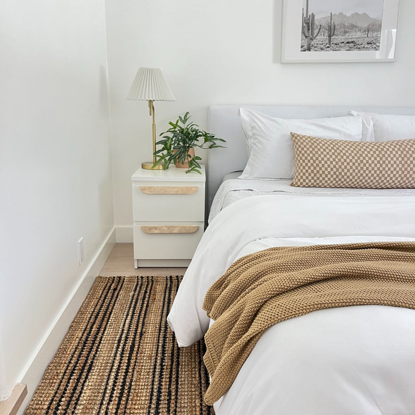 Smith natural bouclé jute runner rug with graphite stripes on the floor next to a bed and nightstand in a modern bedroom.