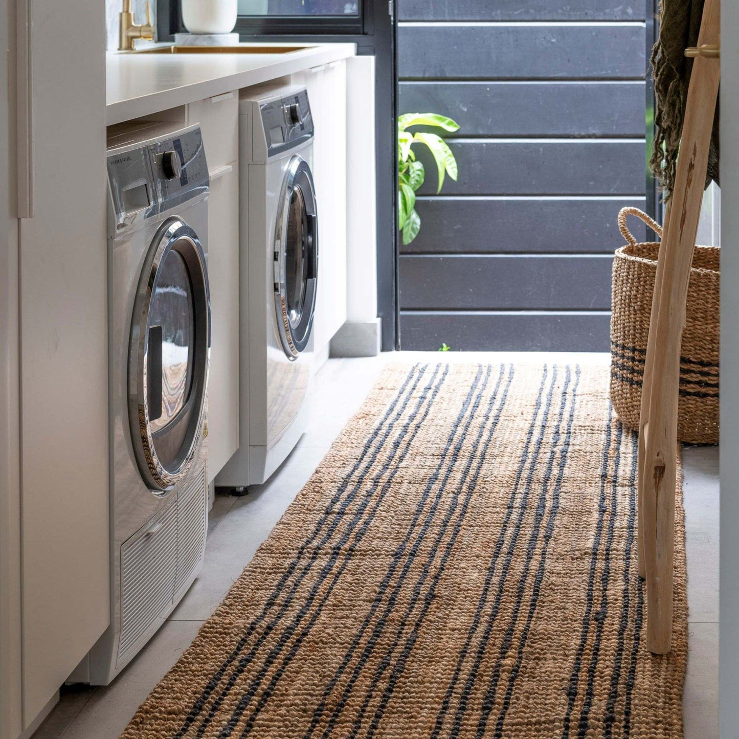 Smith natural bouclé jute runner rug with graphite stripes on tiled floor in a compact modern laundry room.