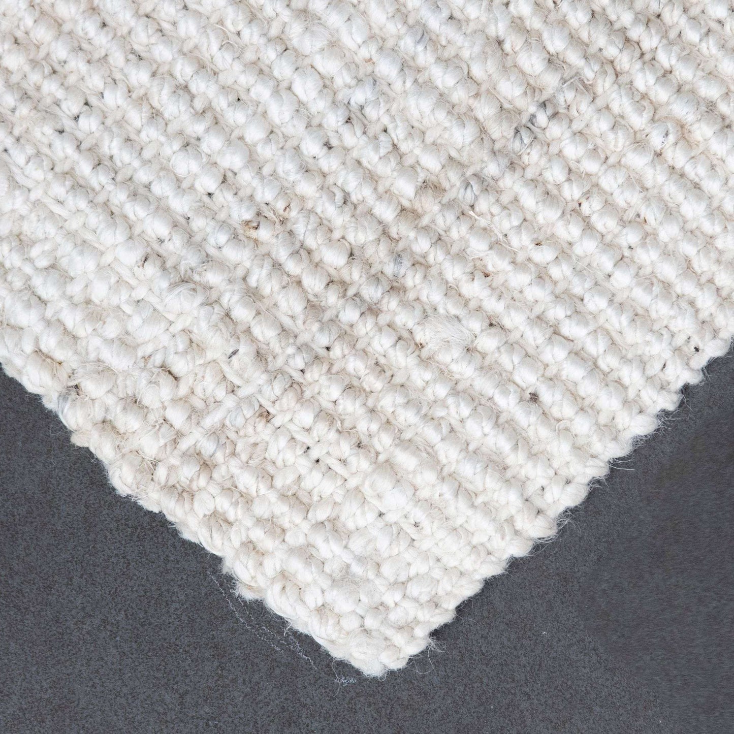 Close-up of Vincent, whitewashed, chunky jute bouclé rug on slate background.