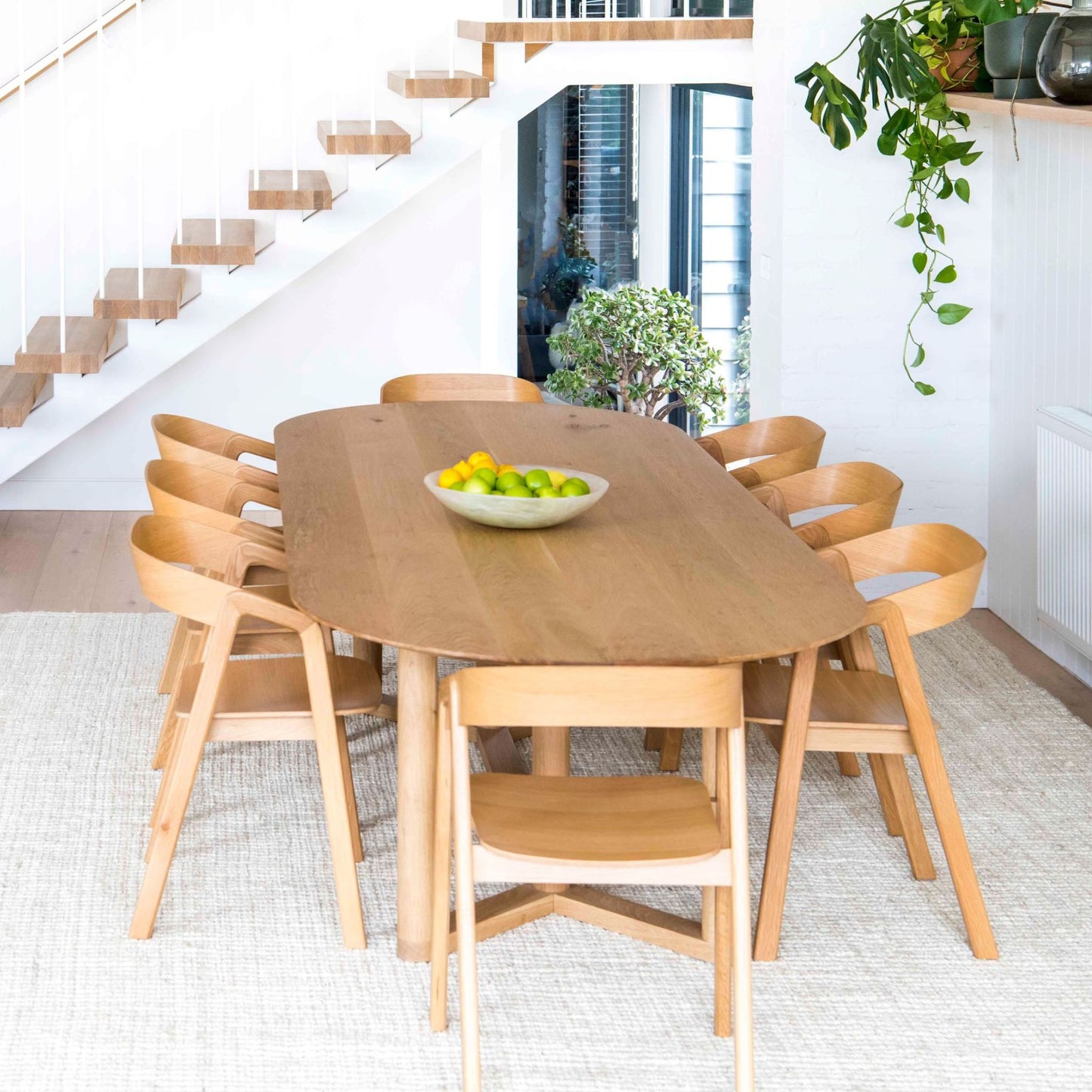 Vincent whitewashed, jute bouclé area rug, under dining table on light wooden floors, in a modern home.