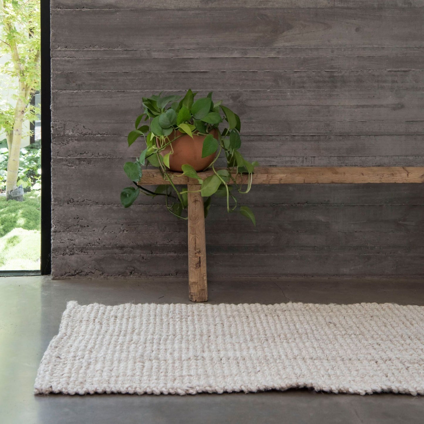 Vincent whitewashed, chunky jute bouclé, oversized mat rug, on polished concrete floors in a modern home.