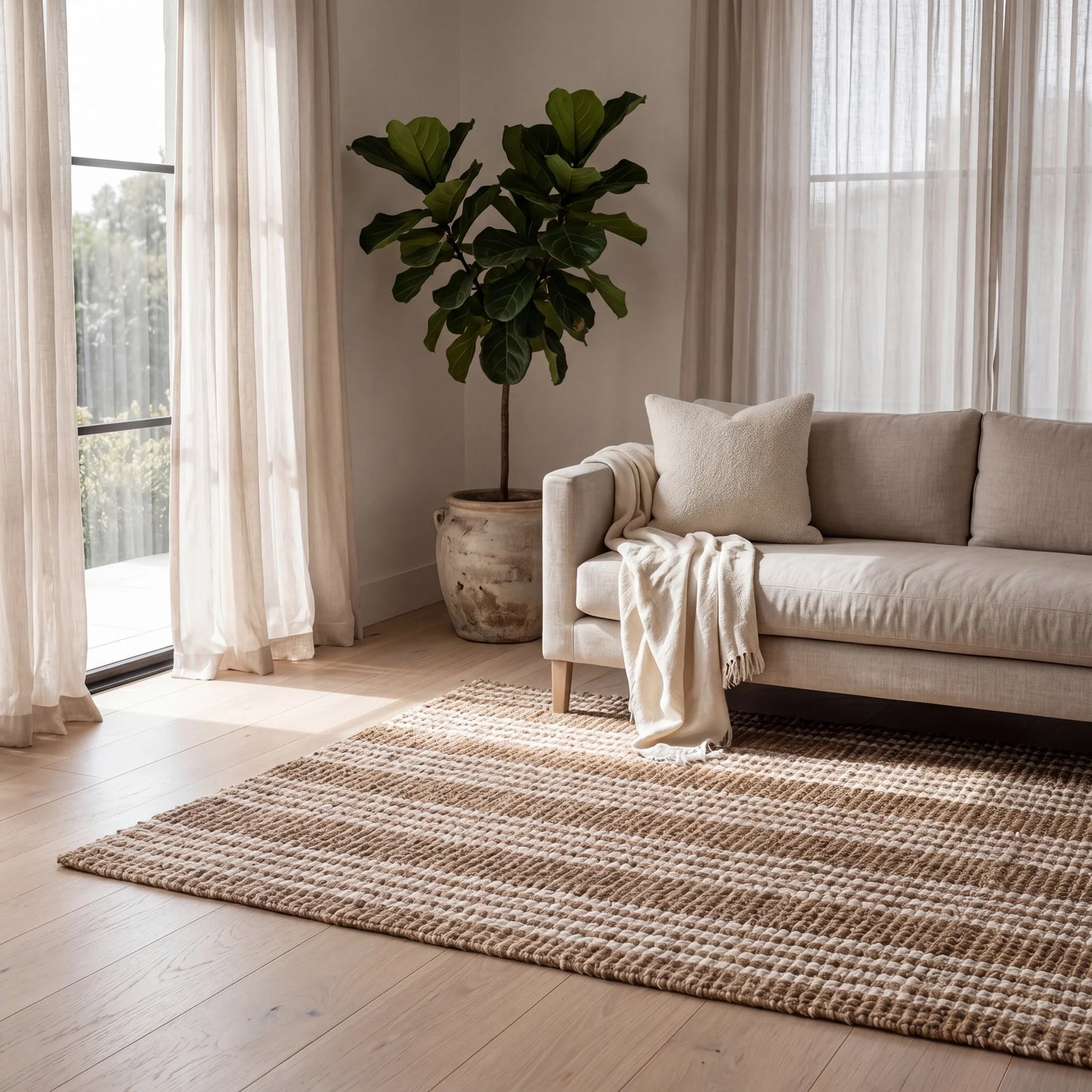 Living room with beige sofa, plant, and striped rug on the floor.