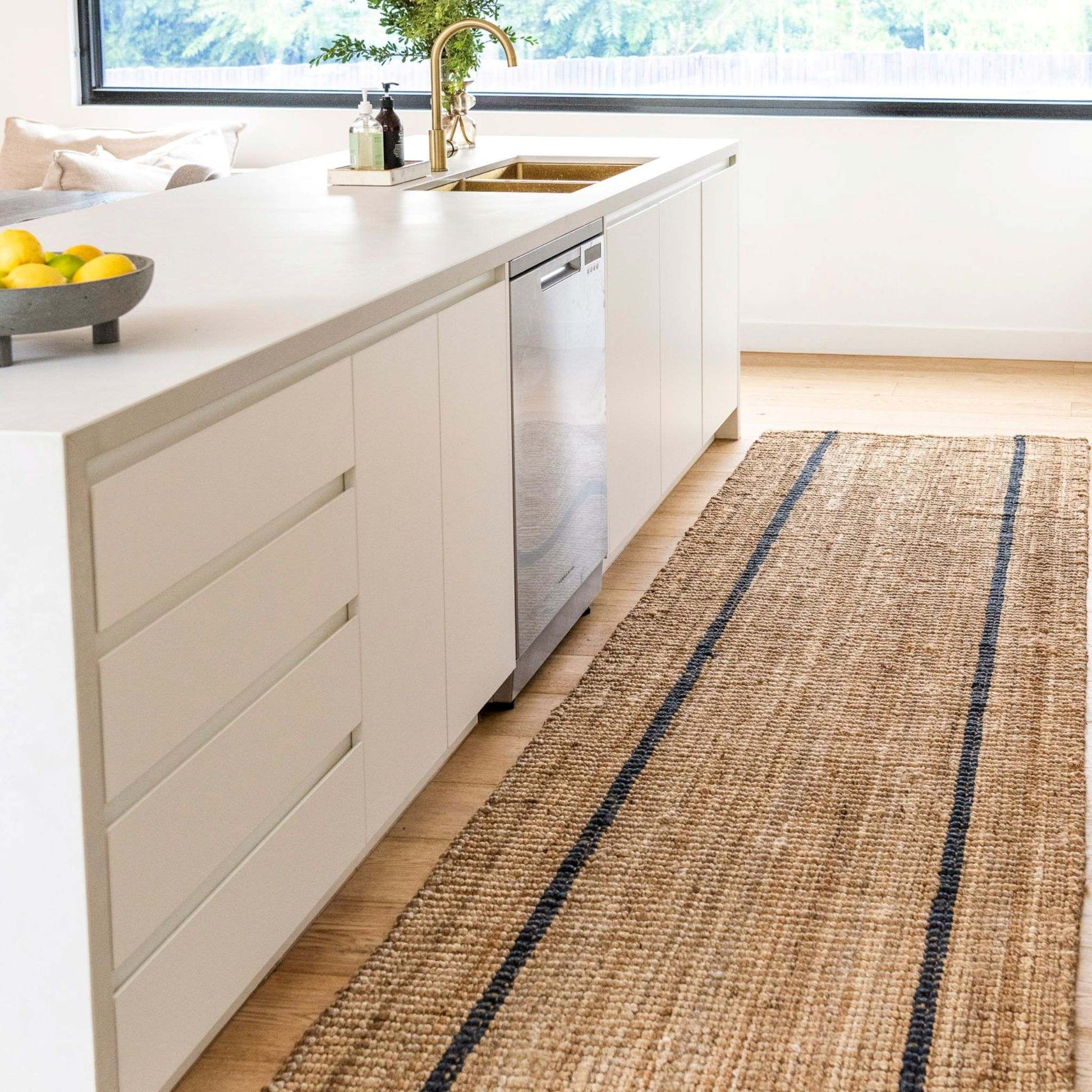 Modern kitchen with a handcrafted striped chunky jute bouclé runner rug in natural color with a graphite stripe.