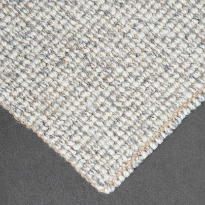 Close-up of Carter handcrafted  grey white heathered wool and jute bouclé rug on slate background.
