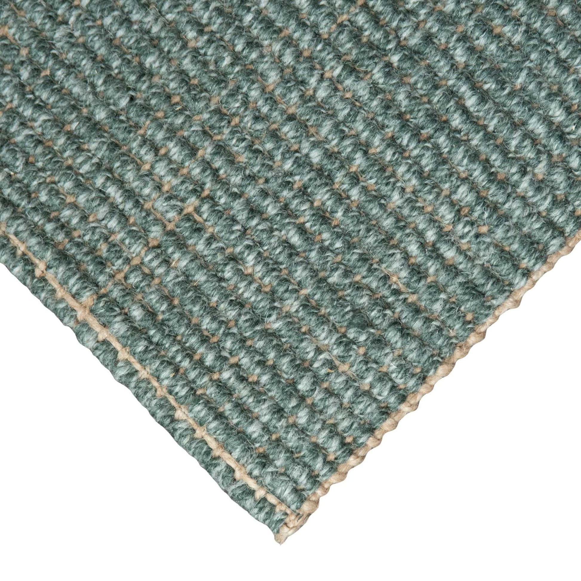 Close-up of Carter Forest handcrafted marled green wool and jute bouclé rug on white background.