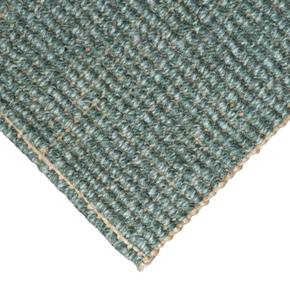 Close-up of Carter Forest handcrafted marled green wool and jute bouclé rug on white background.