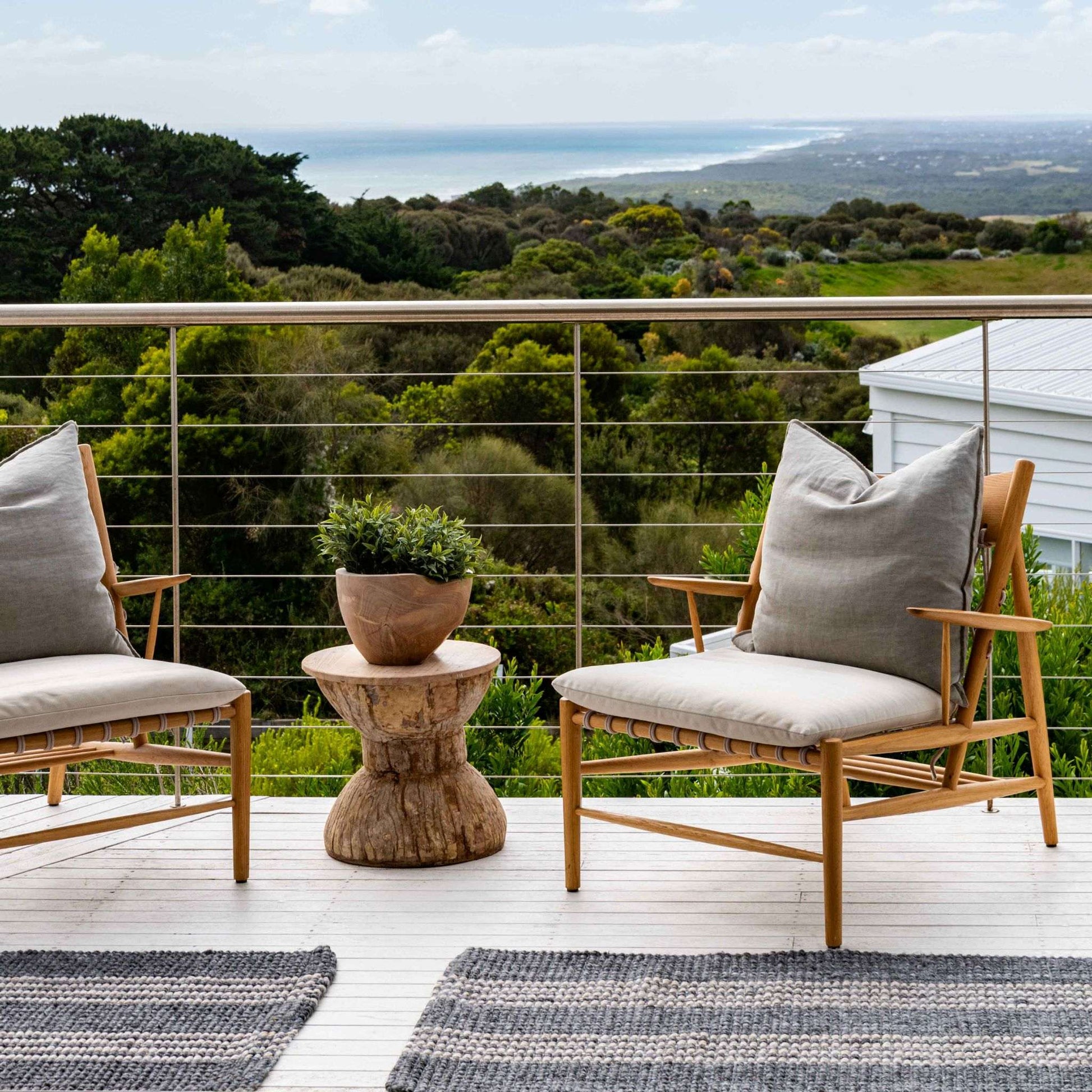 Macintosh flatweave slate grey rug with natural stripes, made from 100% recycled PET, sitting on coastal timber decking. 