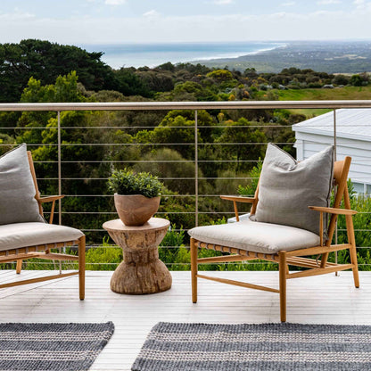 Macintosh flatweave slate grey rug with natural stripes, made from 100% recycled PET, sitting on coastal timber decking. 