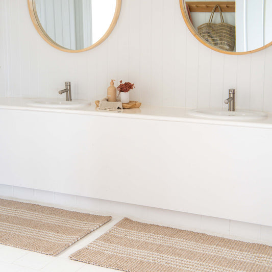 Franklin flatweave rug, with natural and white stripes, made from 100% recycled PET on tile in white, modern bathroon.
