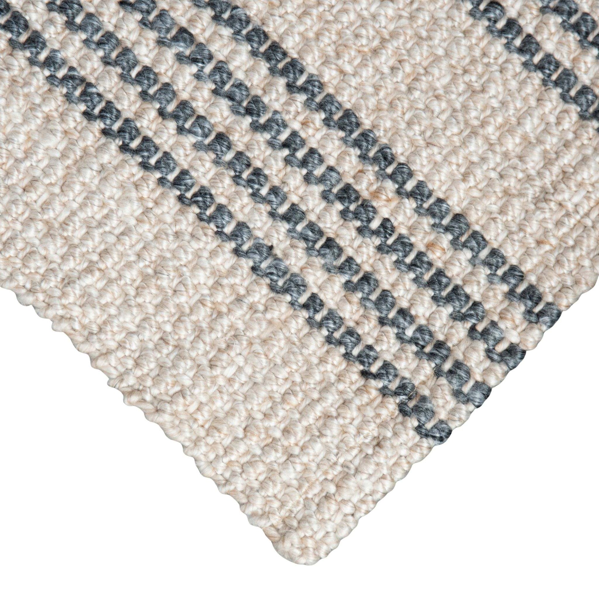 Close-up of Macintosh flatweave rug, with natural and slate grey stripes made from 100% recycled PET with white background.