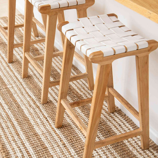 Close-up of modern white stools with the Osbourne natural chunky jute bouclé runner rug with white stripes.