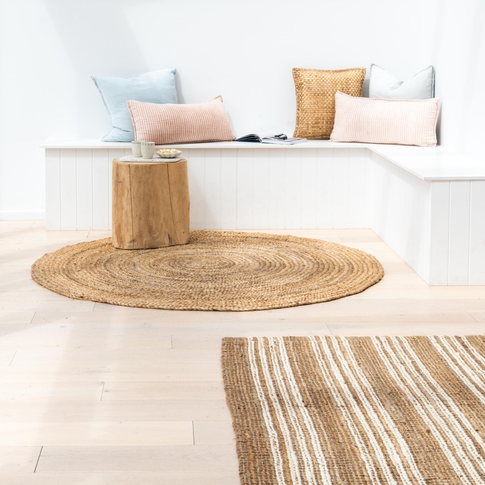 Handcrafted Osbourne natural chunky jute bouclé area rug with white stripes in nook space with white walls and a cozy reading area.