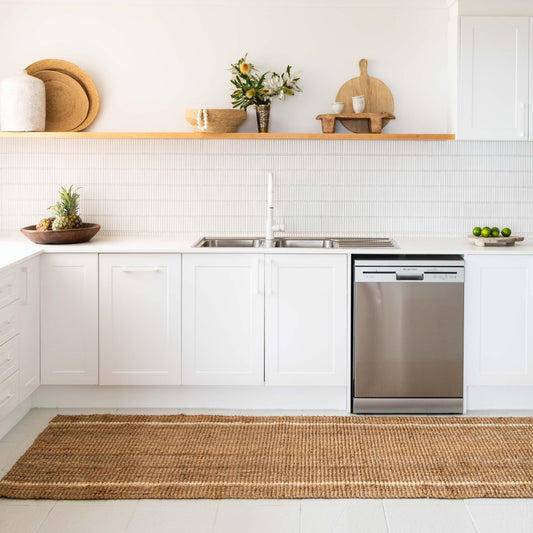 Robinson runner rug in natural bouclé jute with two white stripes on tile floor in modern white kitchen.