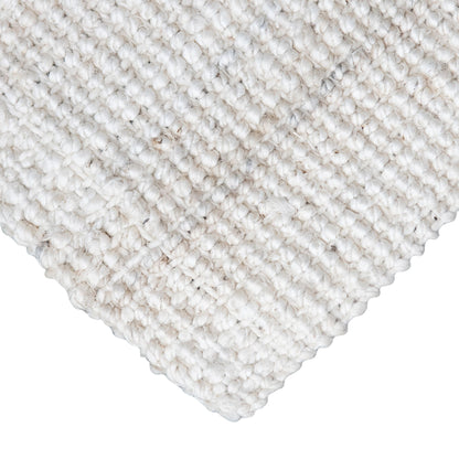 Close-up of Vincent, whitewashed, chunky jute bouclé rug on white background.