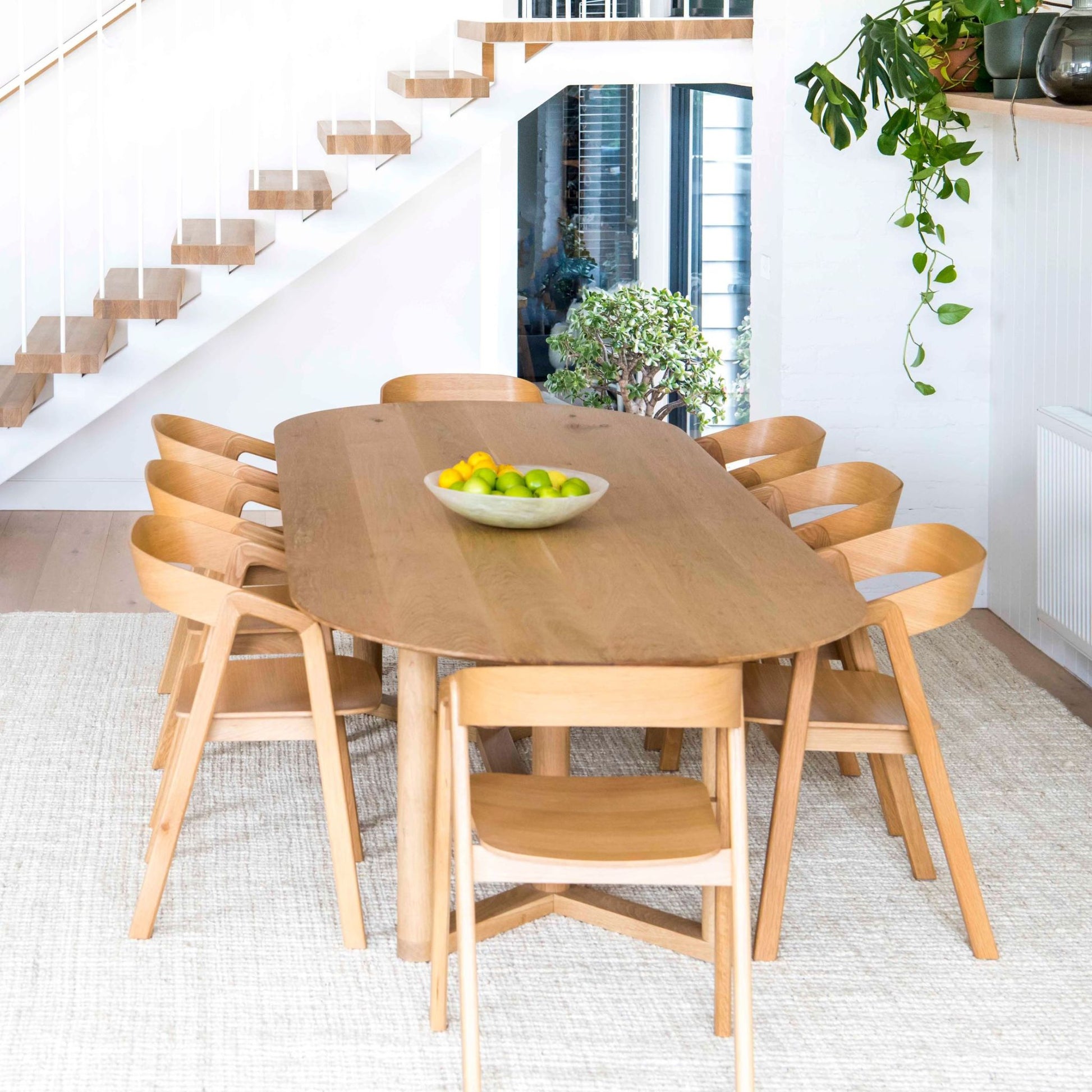 Vincent whitewashed, jute bouclé area rug, under dining table on light wooden floors, in a modern home.  