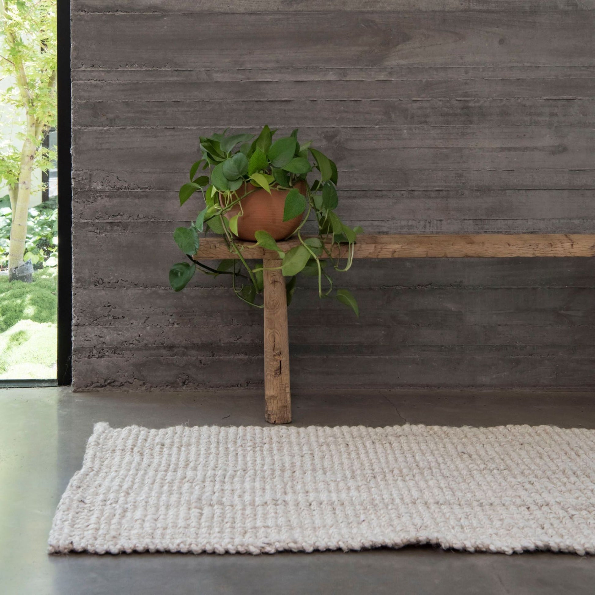 Vincent whitewashed, chunky jute bouclé, oversized mat rug, on polished concrete floors in a modern home.