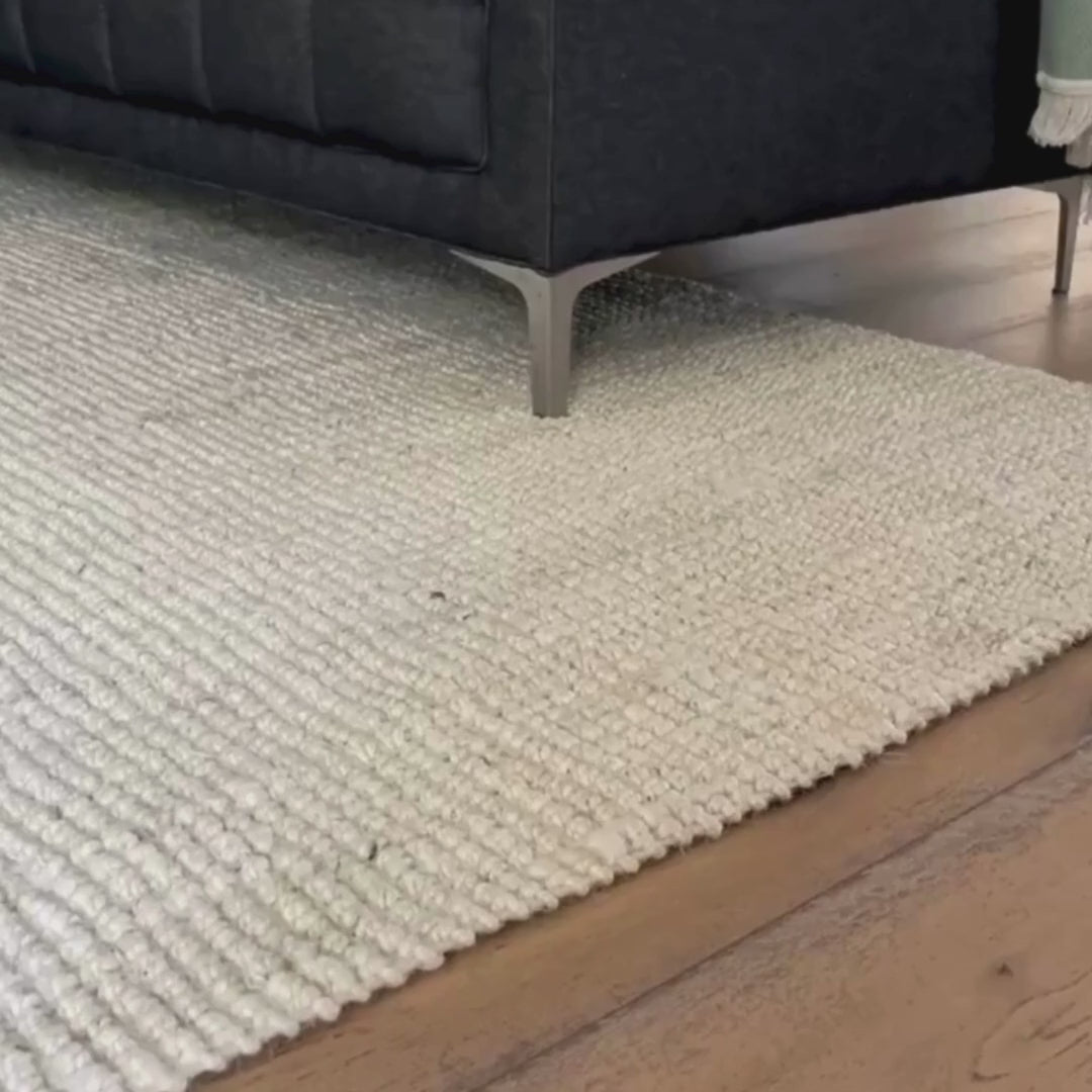 Close-up video of Vincent, whitewashed, chunky jute bouclé rug in a living room.
