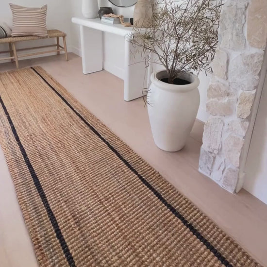 Close-up of the Bailey runner rug with natural woven bouclé texture and graphite stripes at an front door entrance.