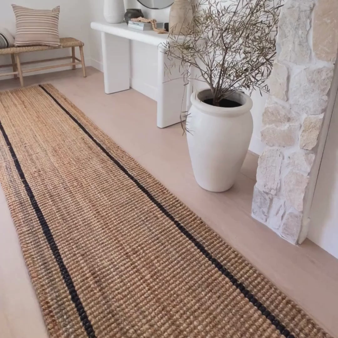 Close-up of the Bailey runner rug with natural woven bouclé texture and graphite stripes at an front door entrance.